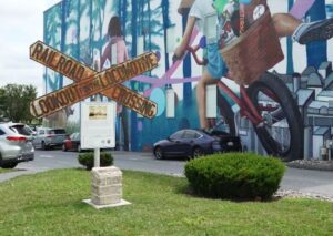 Historic crossbuck sign in front of mural on building
